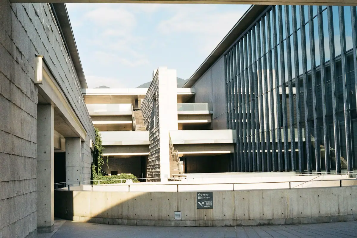 A modern concrete and glass building with an external stair rising along its facade