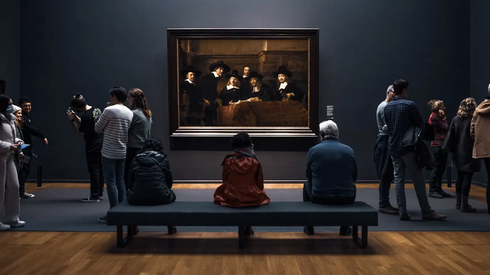A crowd of people gathered around a large artwork inside a busy exhibition space