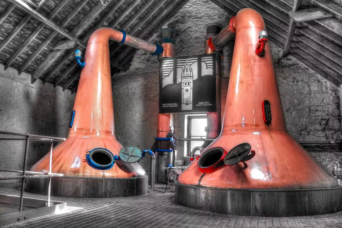 Two copper pot stills standing in a distillery production room