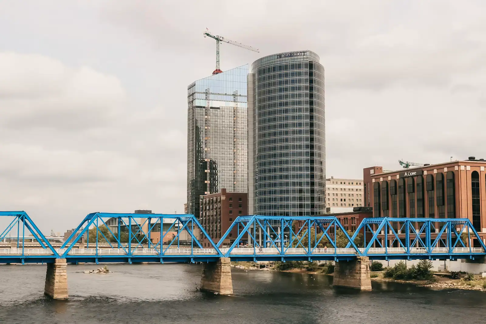 A blue painted pedestrian bridge spanning the Grand River between downtown office blocks