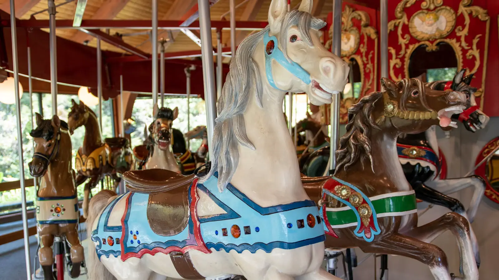 A painted wooden carousel horse with riders on the platform behind it