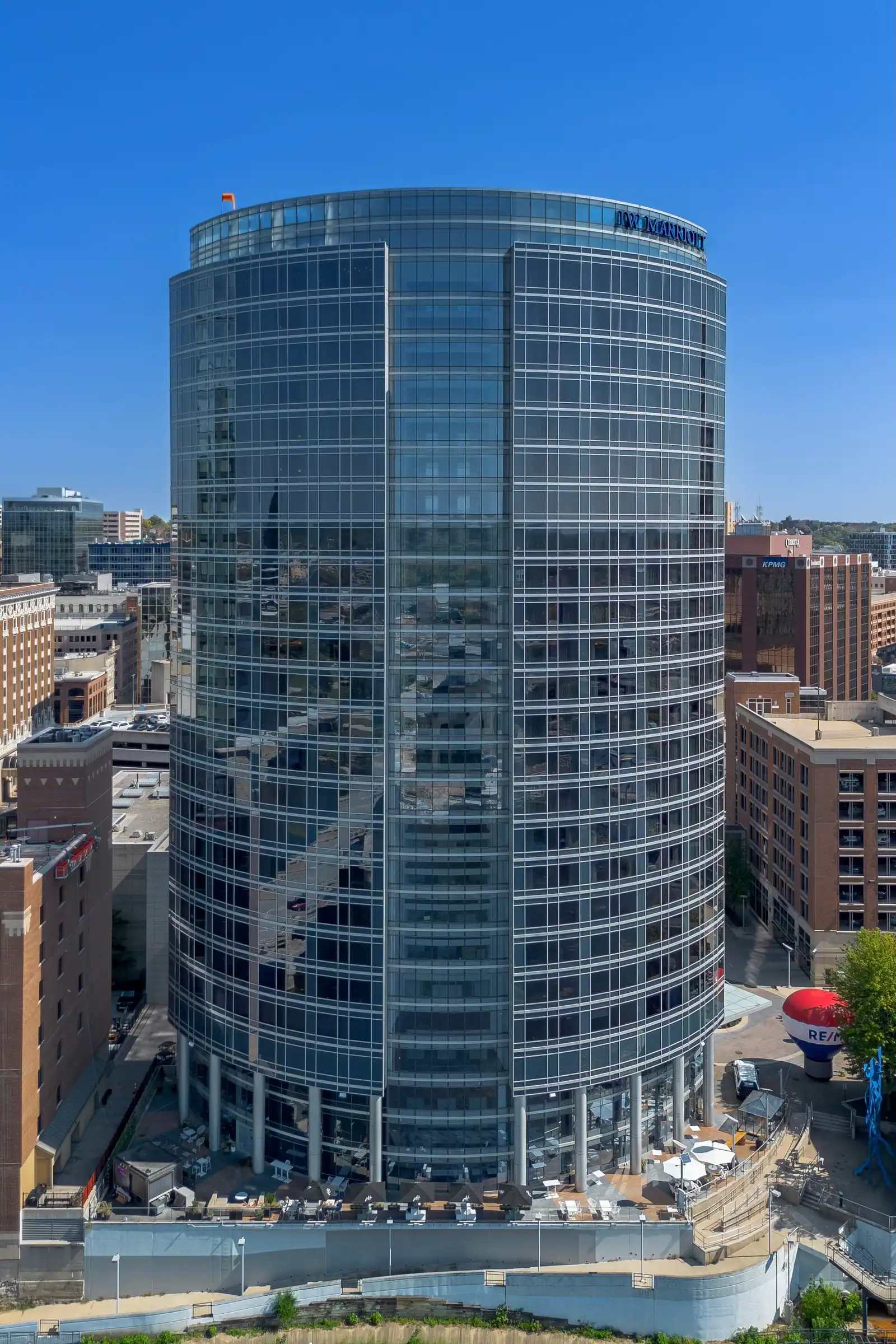A blue steel pedestrian bridge crossing a river in front of downtown buildings