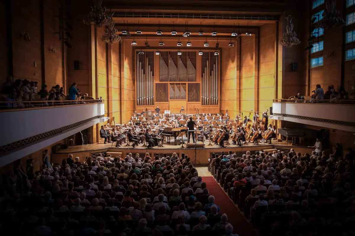 An audience seated in rows watching musicians perform in a large hall