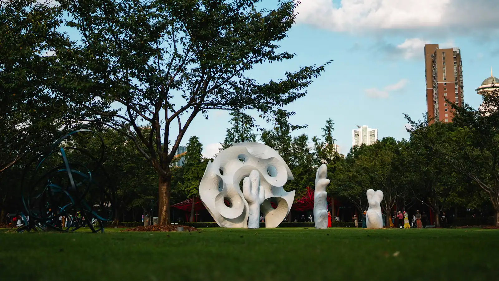 Modern abstract sculptures standing on open mown grass in a park under a pale sky