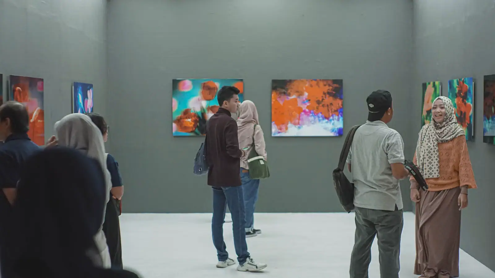 A group of visitors standing in a high-ceilinged museum gallery looking at a large painting