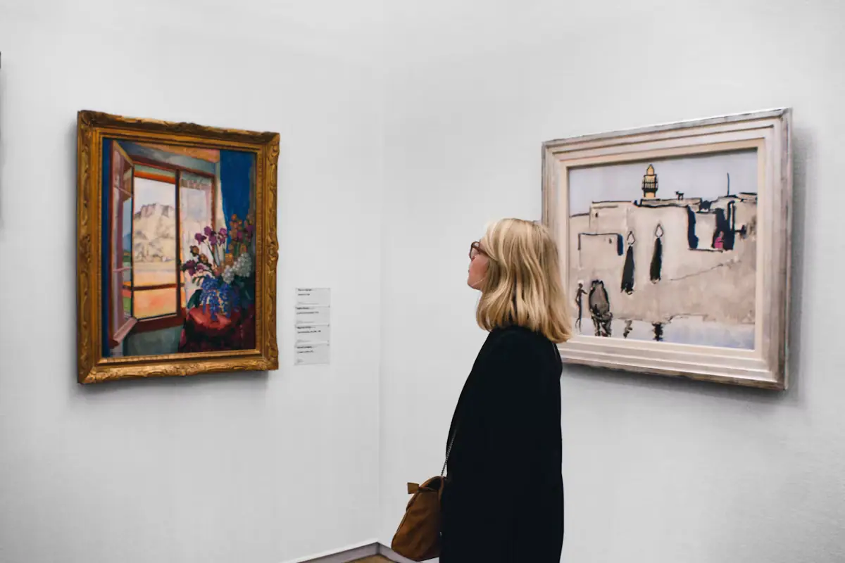 A visitor standing in front of a framed painting in a quiet gallery