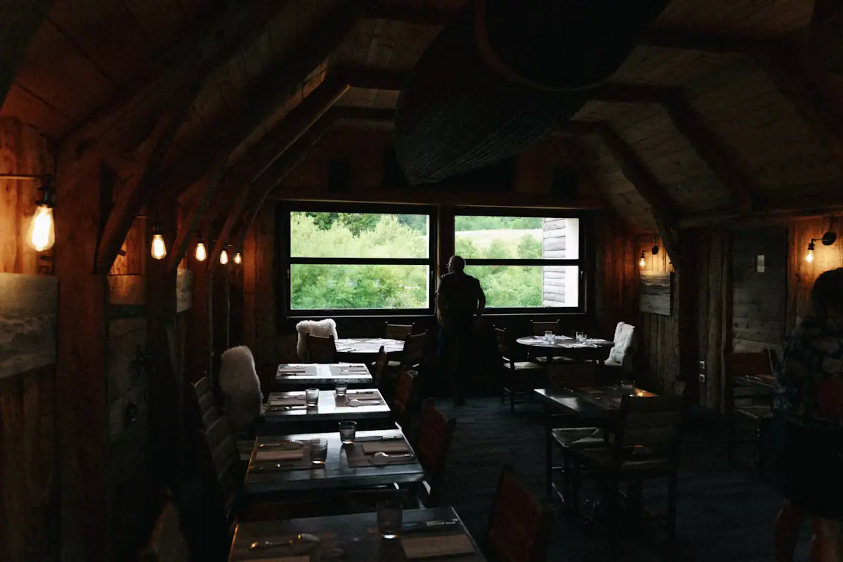 A restaurant interior with wooden tables and large street-facing windows