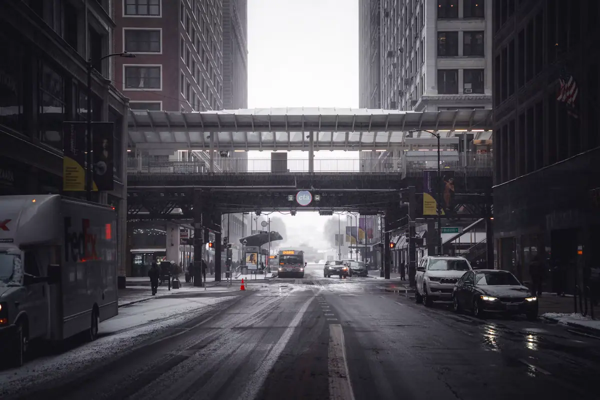 A city street under fresh snow with an overhead walkway crossing between buildings