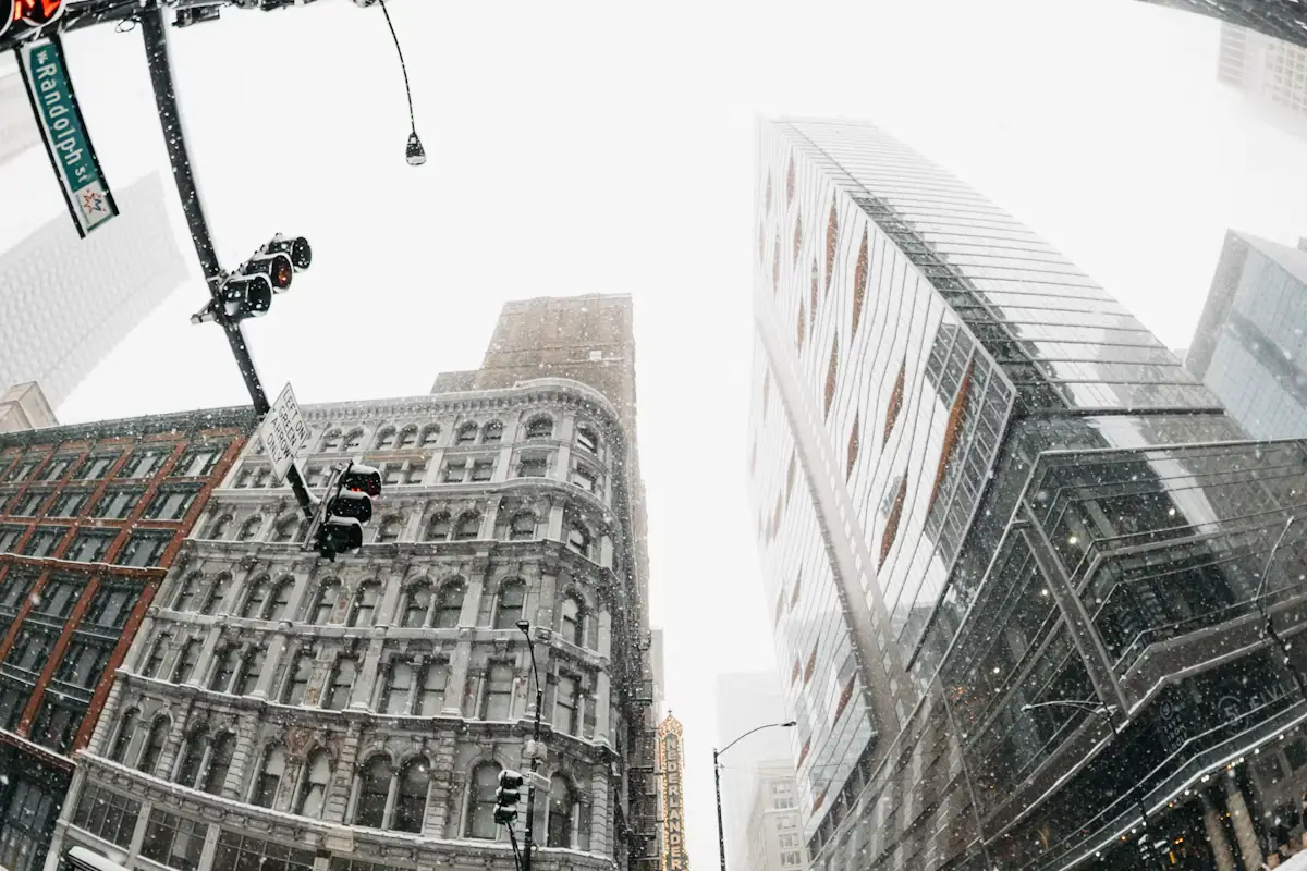 Snow falling on a city street lined with tall buildings
