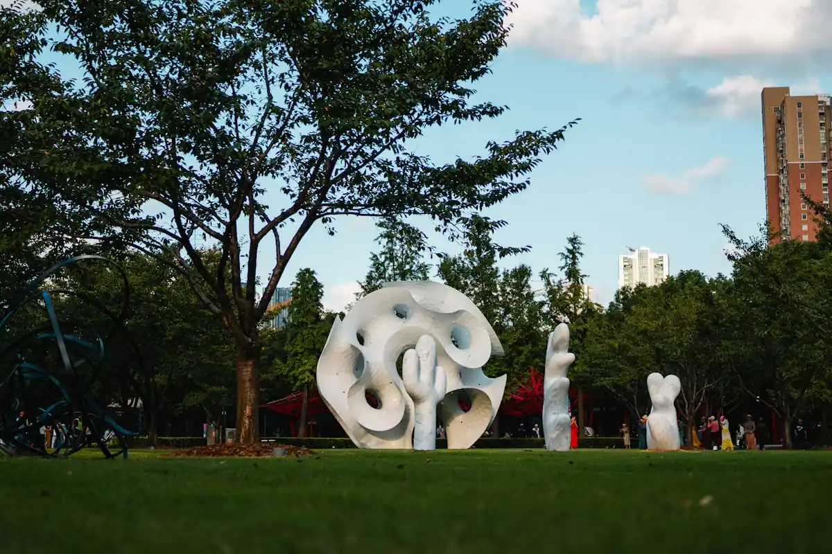 Modern sculptures standing on a mown lawn among trees in a sculpture park