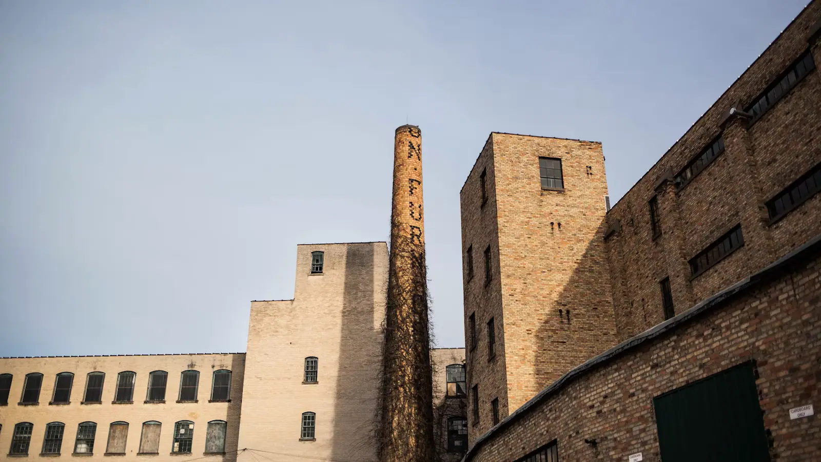 A tall brick warehouse facade with regularly spaced windows under a clear sky