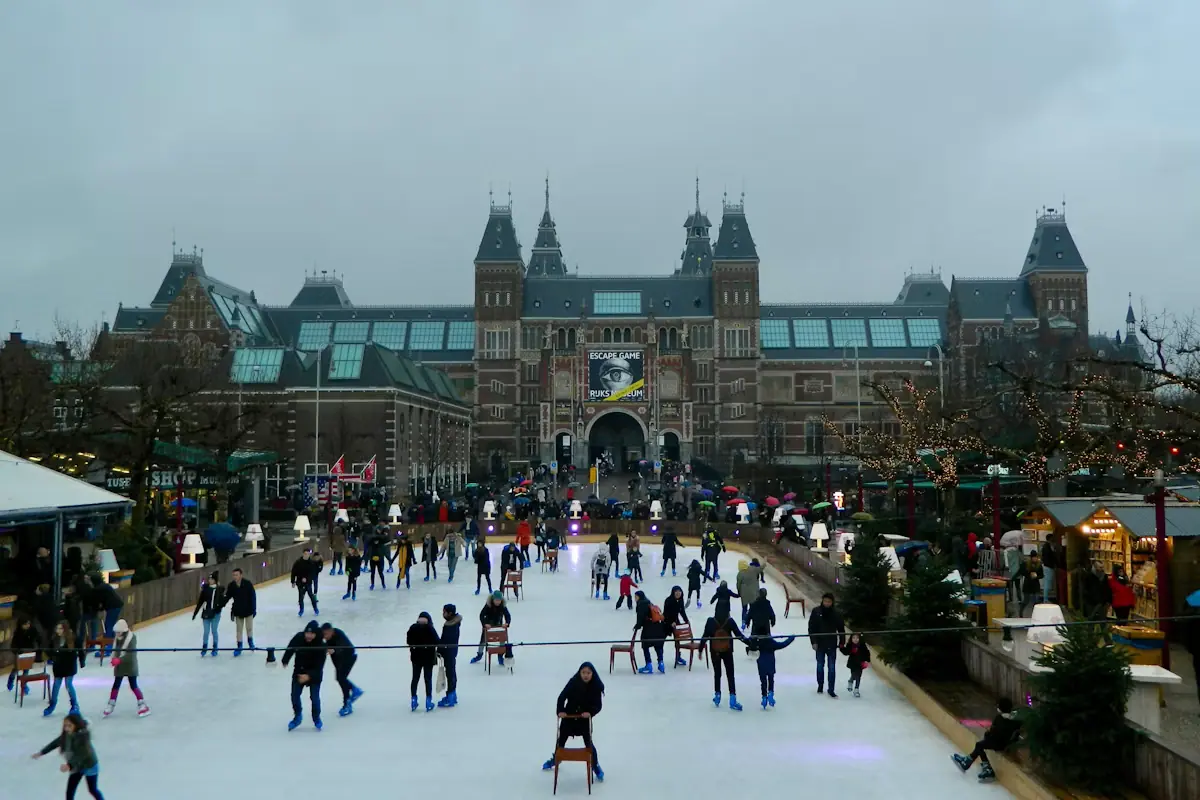 People skating in circles on an outdoor ice rink between city buildings